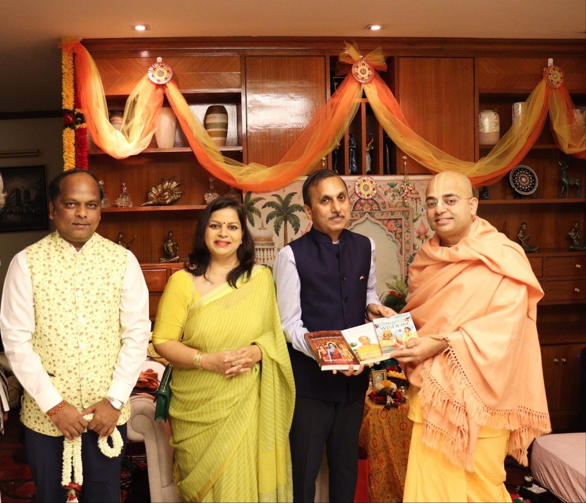 Rahul Laxman Patil, at left, at a cultural exchange gathering where books are being presented, in a room decorated with garlands and traditional textiles.