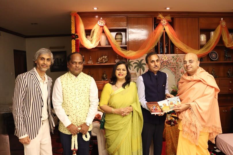 A group including Rahul Laxman Patil at a cultural gathering, standing together as books are presented in a decorated interior.
