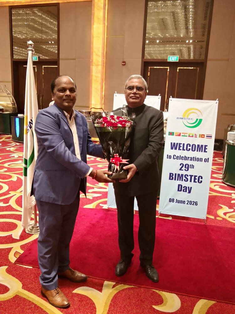 Rahul Laxman Patil presenting a bouquet at the celebration of the 29th BIMSTEC Day, with the BIMSTEC welcome banner and member-state flags behind.