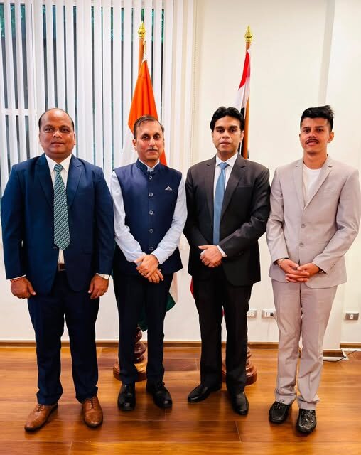 A four-member delegation including Rahul Laxman Patil standing together beside the Indian flag and a partner nation's flag.