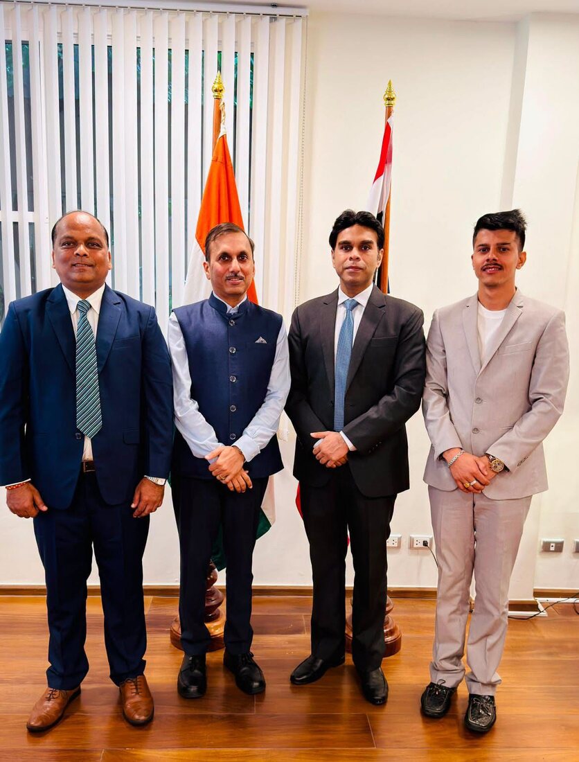 Rahul Laxman Patil with a delegation including a younger participant, standing before the Indian national flag and a partner nation's flag.